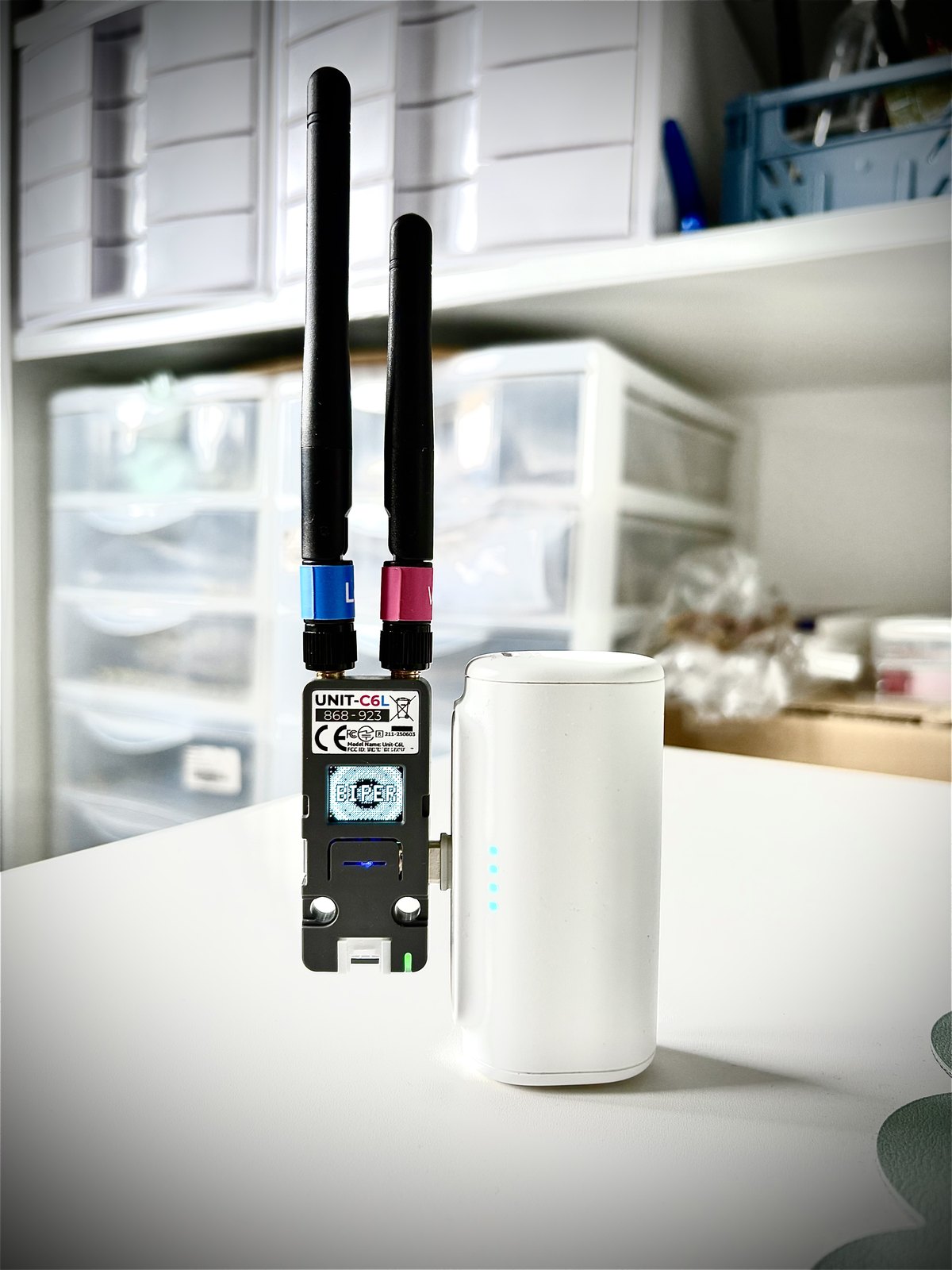 A Biper cube with two antennas; the word BIPER flows across its screen, a power bank alongside